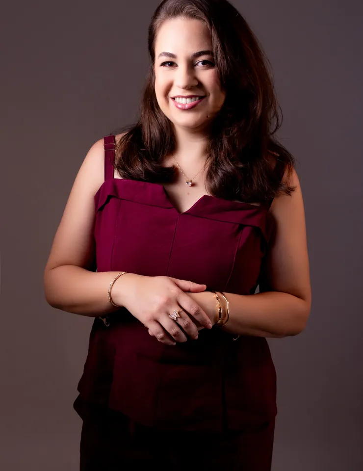 Rebeca Marinho sorrindo sentada em uma poltrona, em retrato profissional